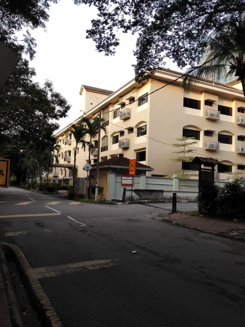 Villa Bolton: A street view of a completed residential building complex, likely an HDB block, at a T-junction with a bus stop and road signage visible.
