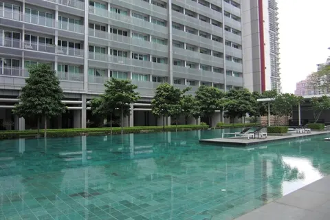 Dua Residency: A swimming pool with turquoise water and a small floating platform with lounge chairs in front of a modern high-rise building.
