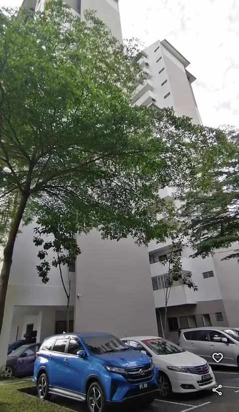 Apartment Seri Ceria 1: An exterior view of a high-rise residential building, showing its white facade and ground level with cars parked in the foreground.