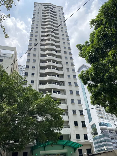 Seri Raja Chulan: A tall white residential tower with wavy balconies, seen from the ground looking up, surrounded by trees and other buildings.