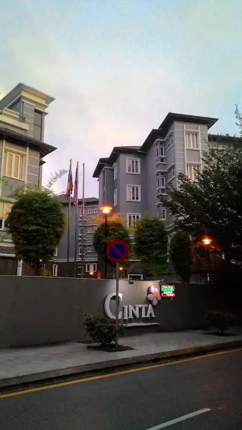 Cinta: A view of the entrance to the 'Cinta' development, featuring a sign on a wall and multi-storey residential buildings in the background.