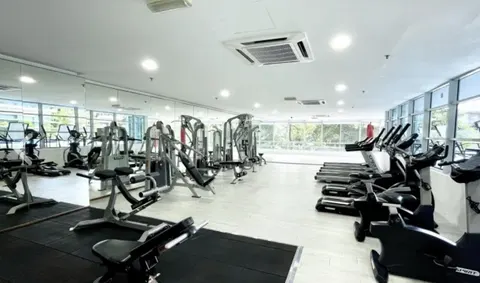 One Residency, KL: A well-lit gym equipped with treadmills, weight machines, and mirrors along the walls.