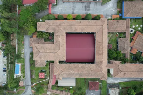 De Rozelle: Aerial top-down view of a complex building with a large central courtyard and brown tiled roofs, surrounded by greenery, roads, and parking areas.