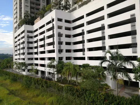 Residensi Puchongmas: The multi-story exterior of a white residential parking structure with dark vertical fins and surrounding greenery, with a high-rise tower visible in the background.