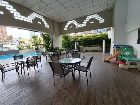 Angkasa Impian 1: A semi-outdoor amenity lounge with seating and a pool, located next to a small children's playground.