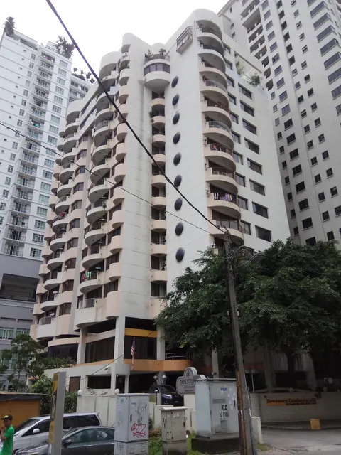 Downtown Condominium: A low-angle shot of the white, multi-story facade of the Downtown Condominium building, showing its balconies, oval windows, and entrance sign, surrounded by other residential buildings and trees.