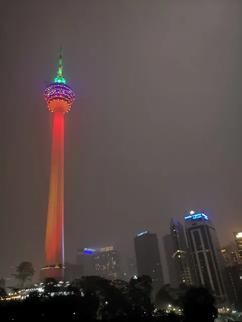 Menara Antara: A night photograph looking up at the brightly lit Menara KL tower and surrounding city skyscrapers from below.