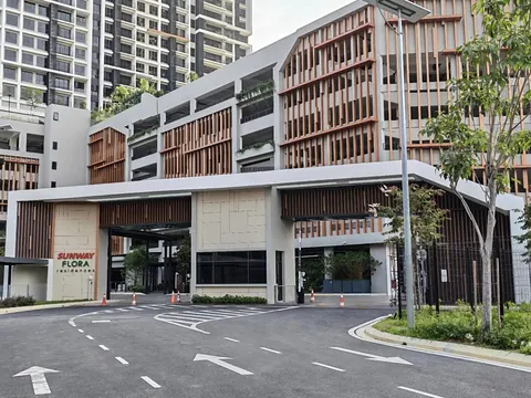 SUNWAY FLORA RESIDENCES: A photograph of the exterior entrance and facade of the Sunway Flora Residences, showing a parking structure with wooden slats, a drive-up canopy, and surrounding roads.