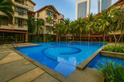 183 Ampang: A swimming pool in a tropical residential development, surrounded by low-rise apartment buildings and palm trees.