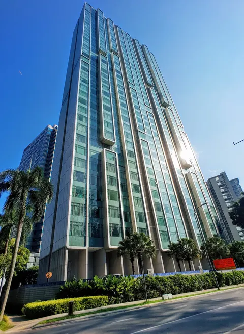 Quadro Residences: A low-angle exterior shot of a tall residential building with a modern glass facade and protruding bay window sections, set against a blue sky with palm trees in the foreground.
