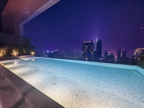 Skyline Embassy: An illuminated infinity pool on a rooftop at night with the city skyline in the background.