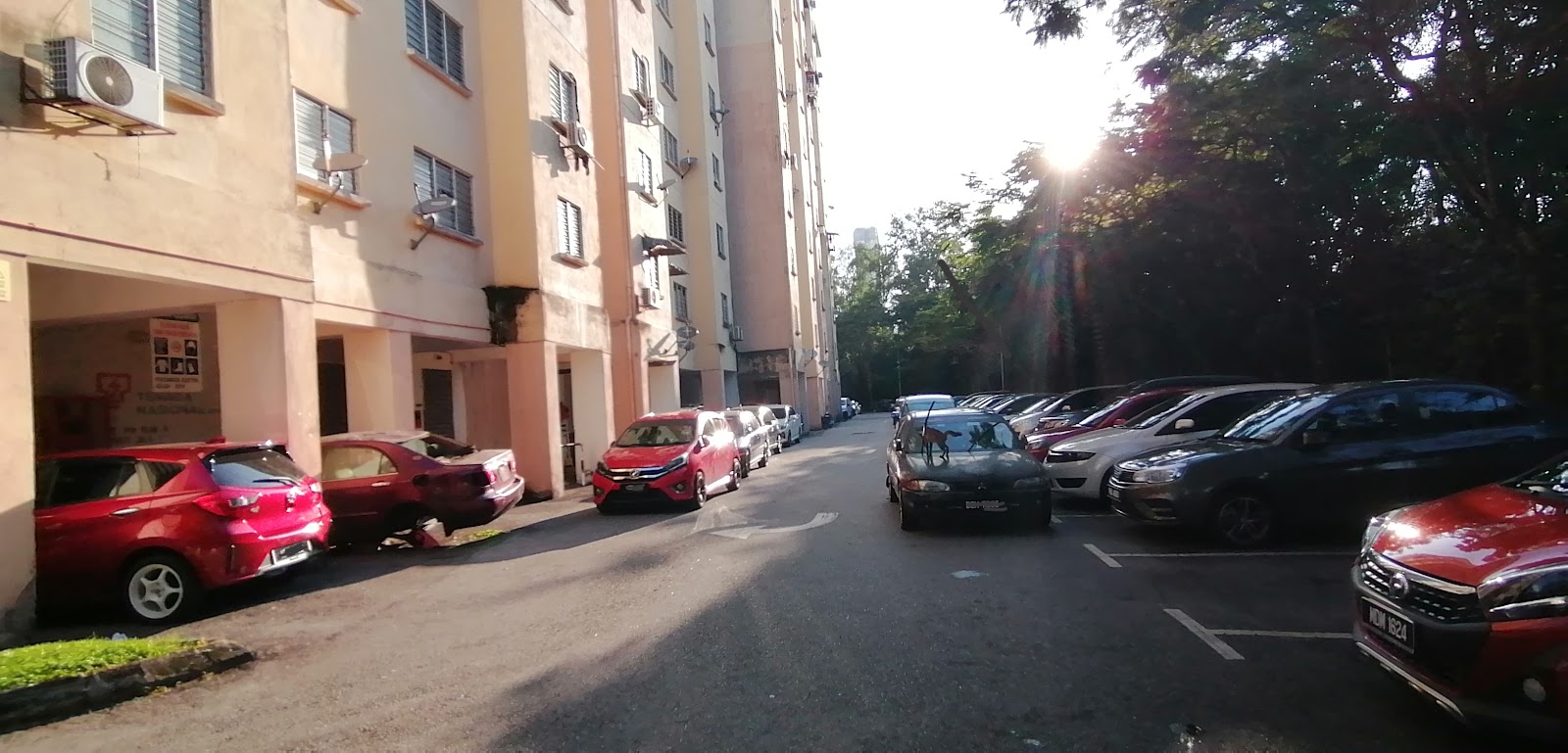 PPR Pinggiran Bukit Jalil: A residential street within a development showing multi-story apartment blocks with a parking area on the side.