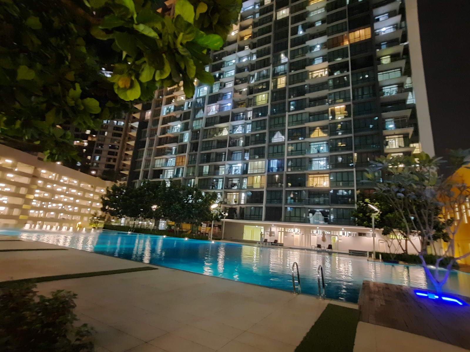 The Z Residence: A swimming pool at night with the illuminated facade of a residential high-rise in the background.