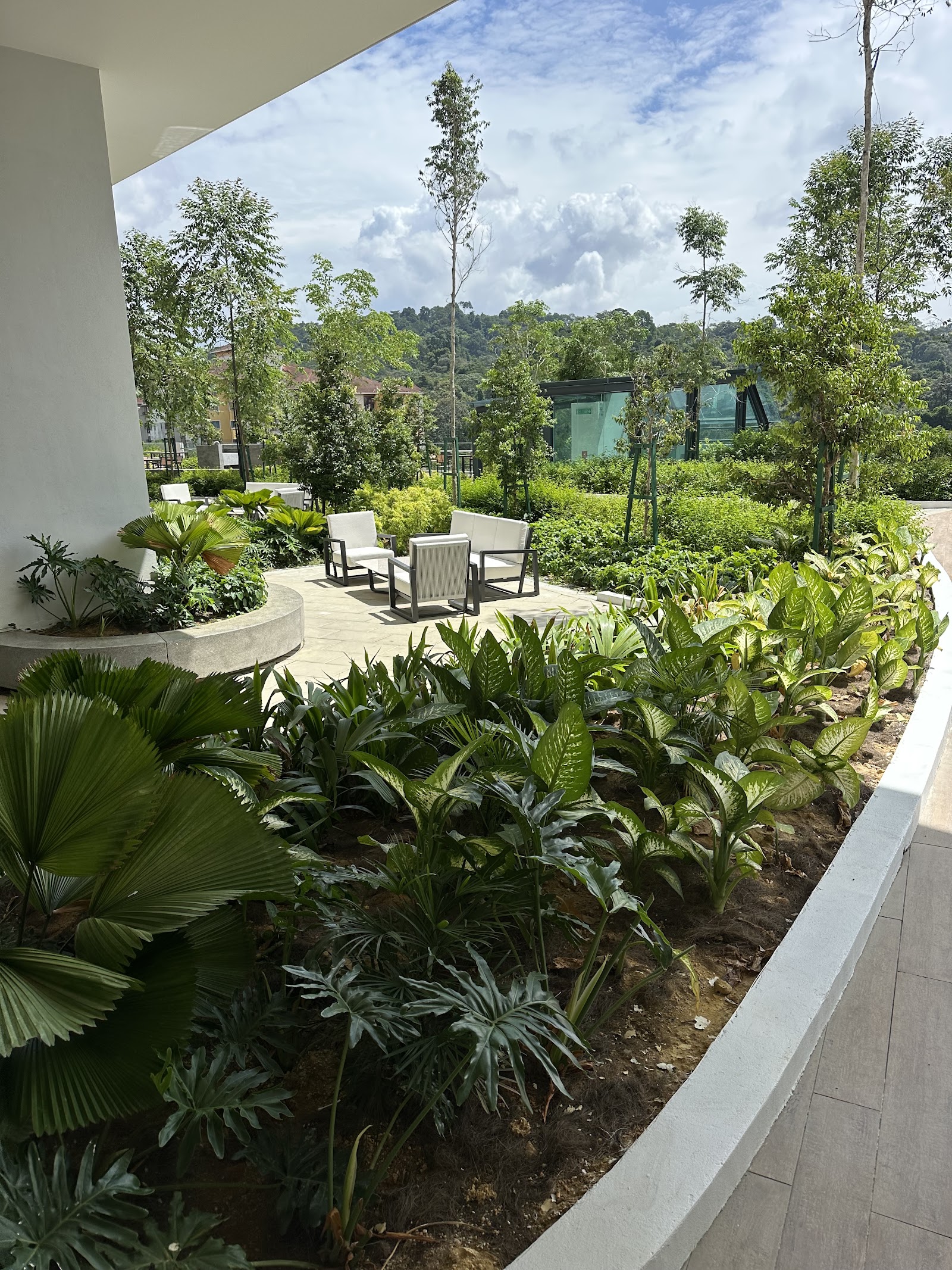 SUNWAY D'HILL RESIDENCES, PETALING JAYA: A landscaped garden courtyard with seating, lush greenery, and a view of distant hills.