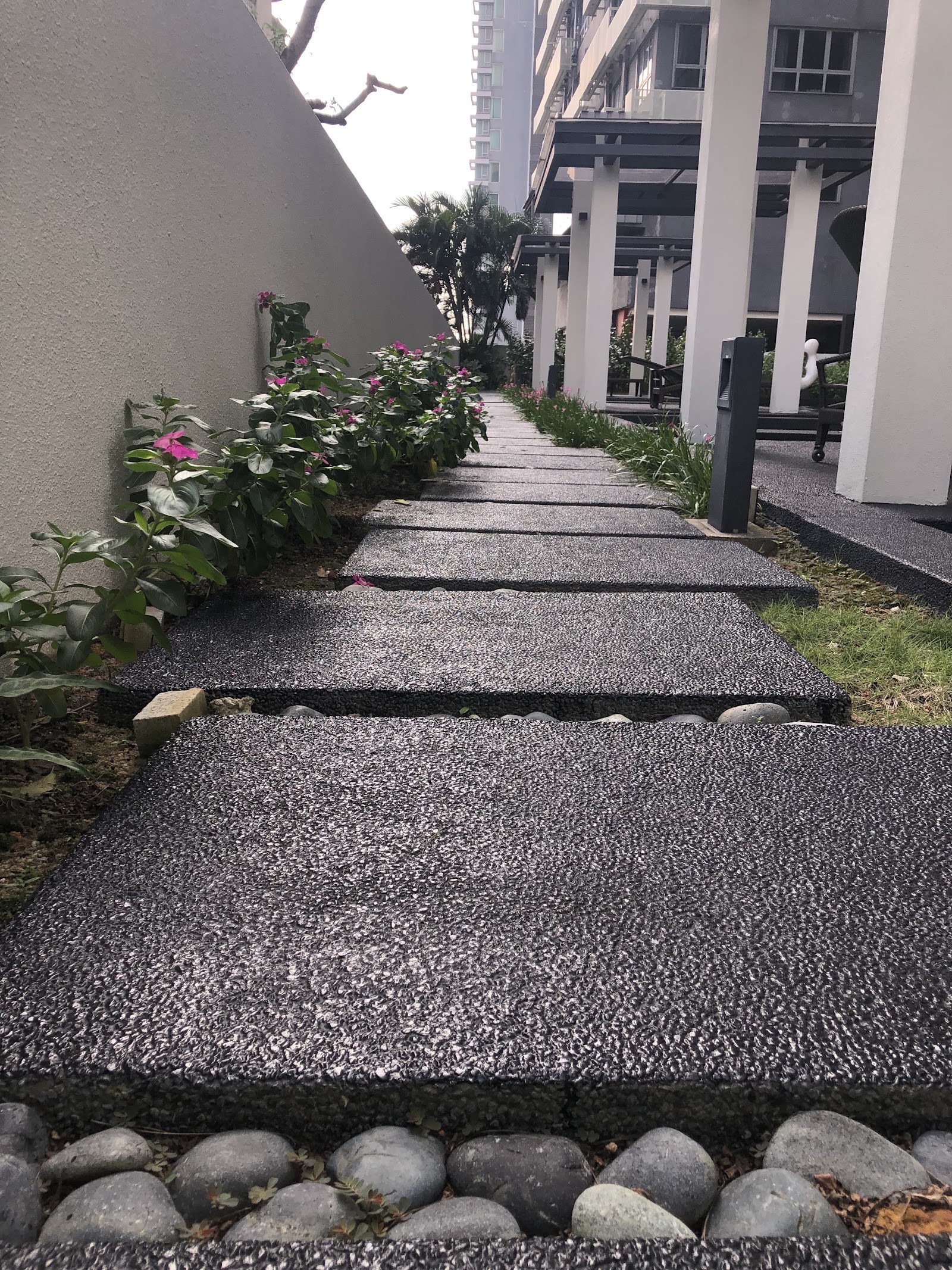 Laman Ceylon, KL: A garden walkway with stepping stones flanked by flowers, leading towards a covered seating area.
