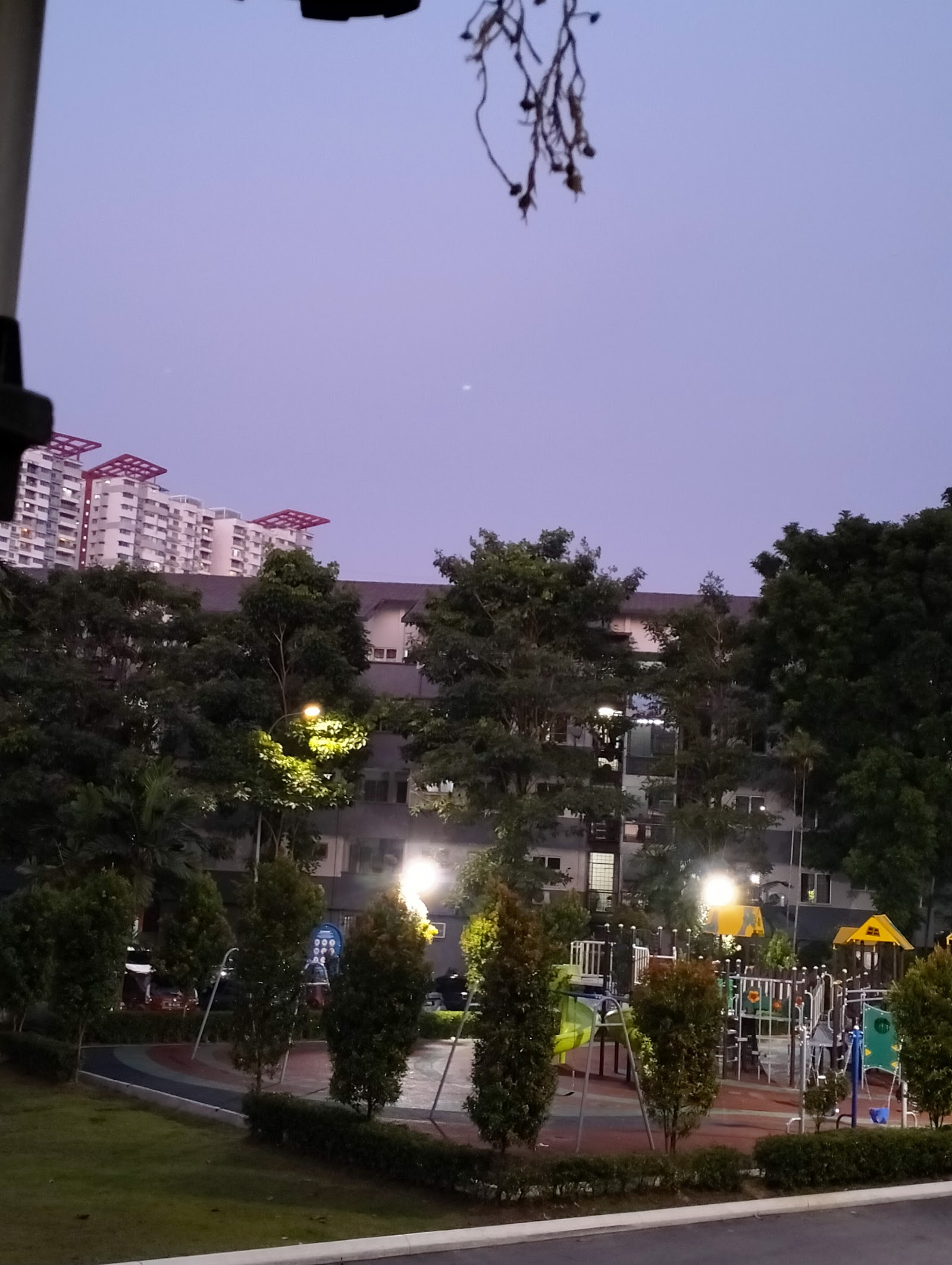 SUNWAY VILLA APARTMENT: View of a playground, trees, and apartment buildings at dusk.