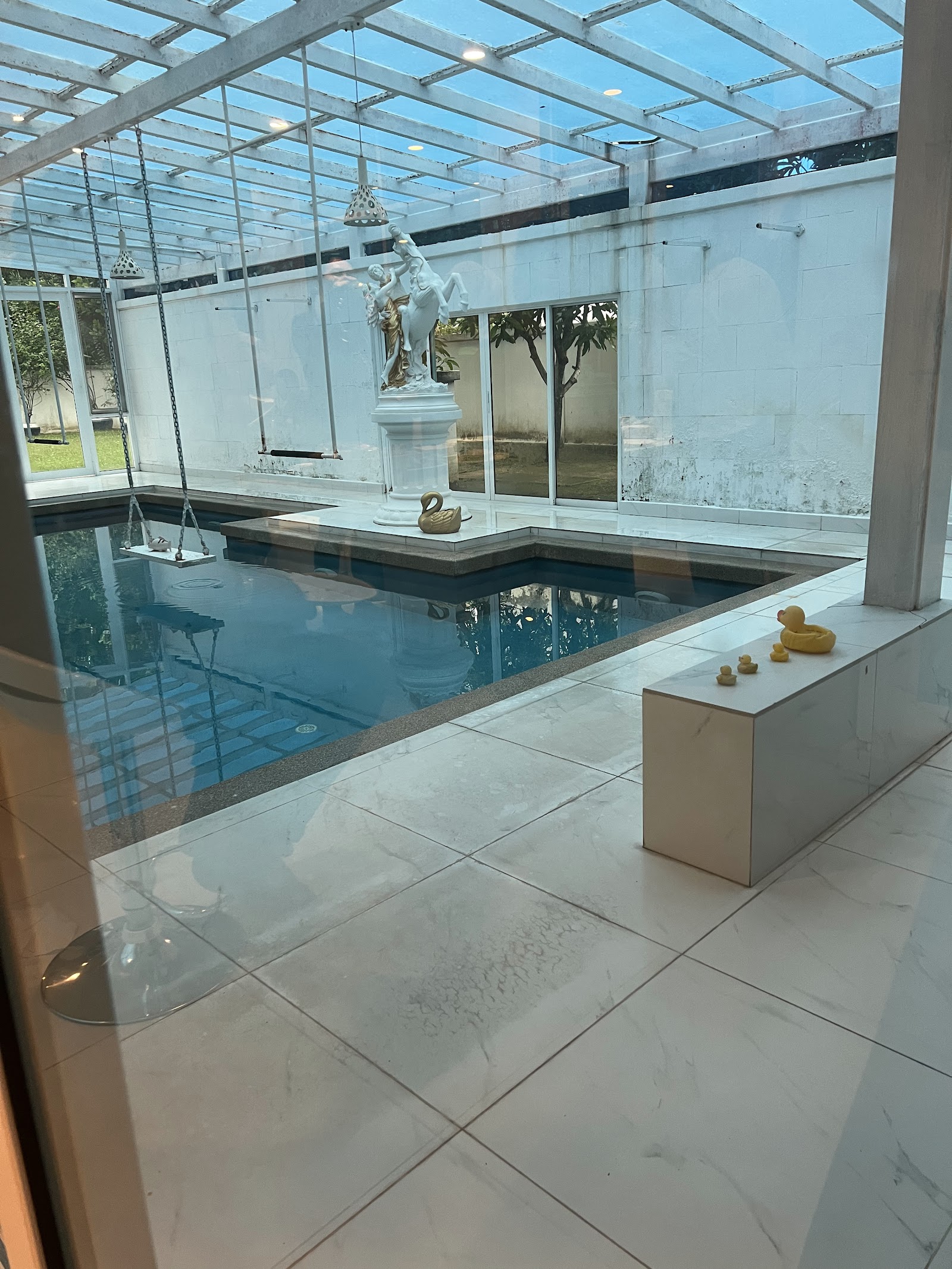 SUNWAY GEOSENSE: A sunken pool with a white marble floor, featuring a horse and rider statue, a swing, and decorative duck sculptures.