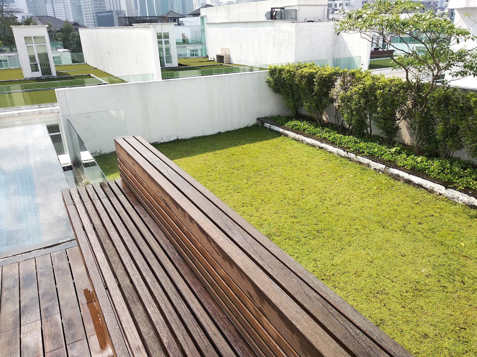Nobleton Crest: An outdoor wooden deck next to a pool overlooking a green lawn and white boundary walls.