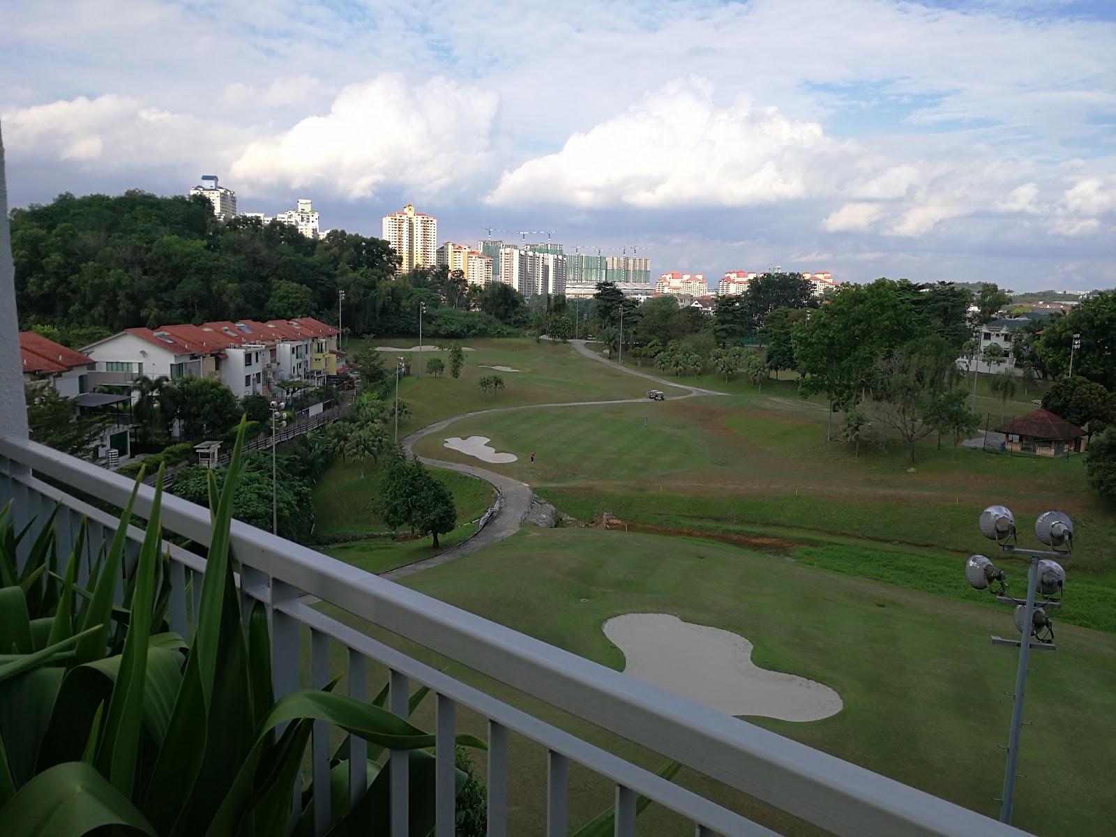 KM1: A view of a golf course and surrounding residential buildings from a balcony.