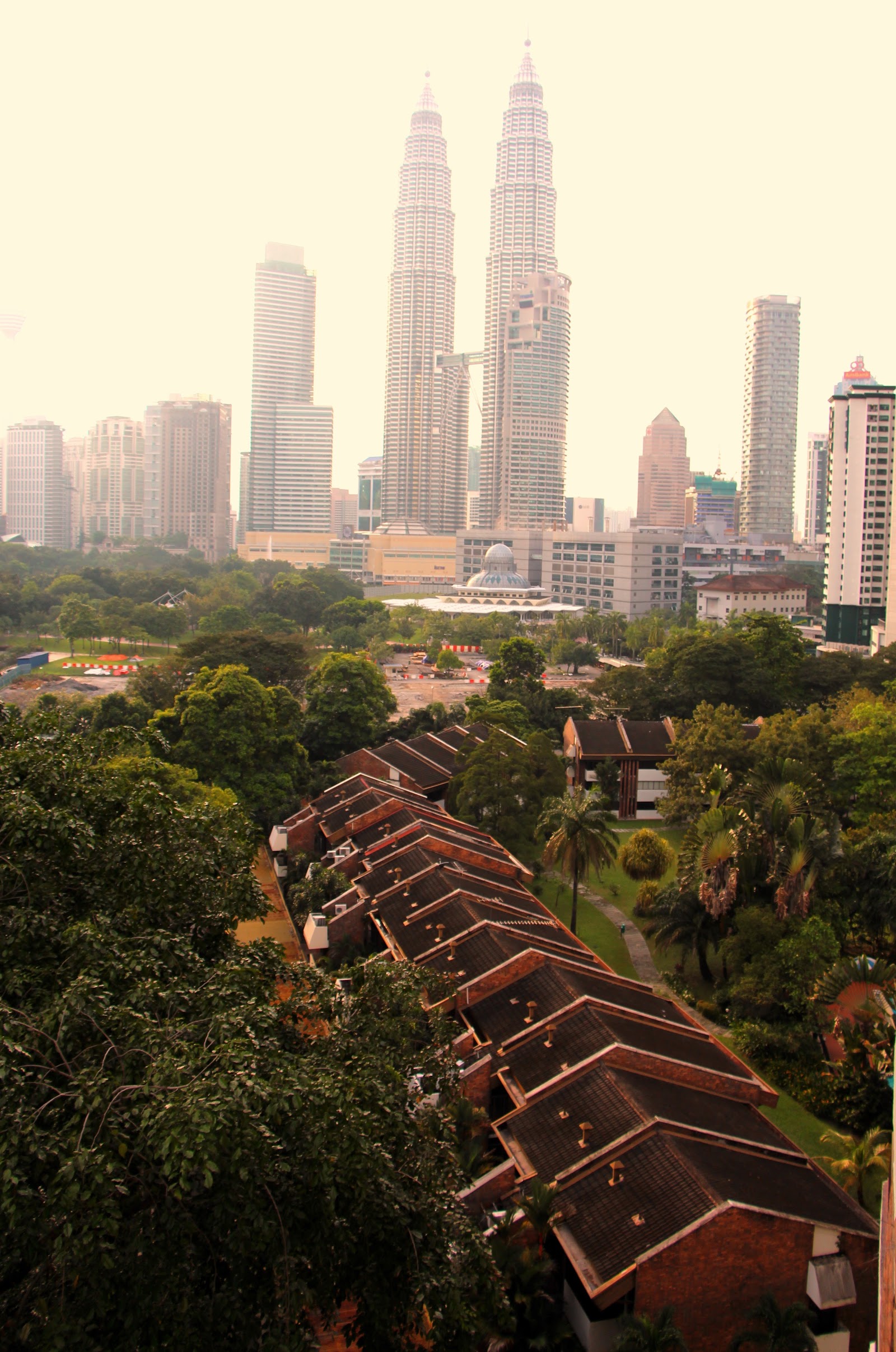 Desa Kudalari: An elevated view looking out from a residential area with row houses towards the Kuala Lumpur skyline featuring the Petronas Twin Towers.
