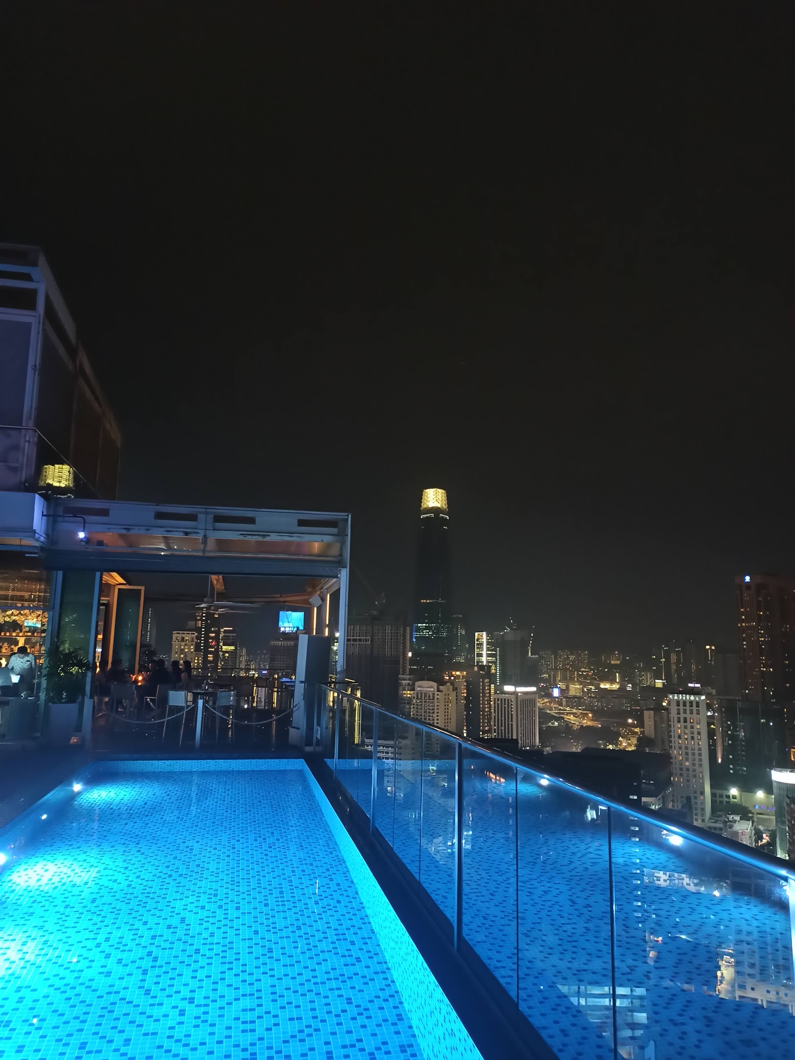 Laman Ceylon, KL: A rooftop infinity pool and bar area at night, looking out over the Kuala Lumpur city skyline.