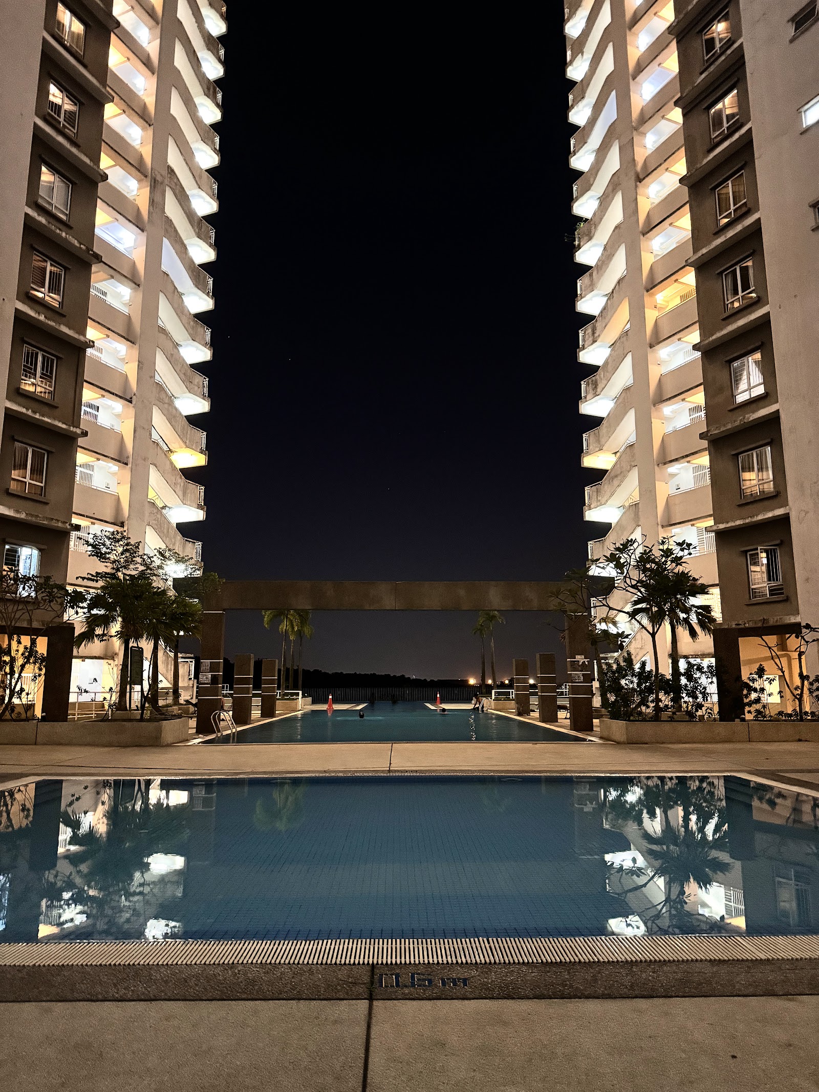 Cova Suites: A nighttime view of the swimming pool area at Cova Suites, located between two lit high-rise residential towers.