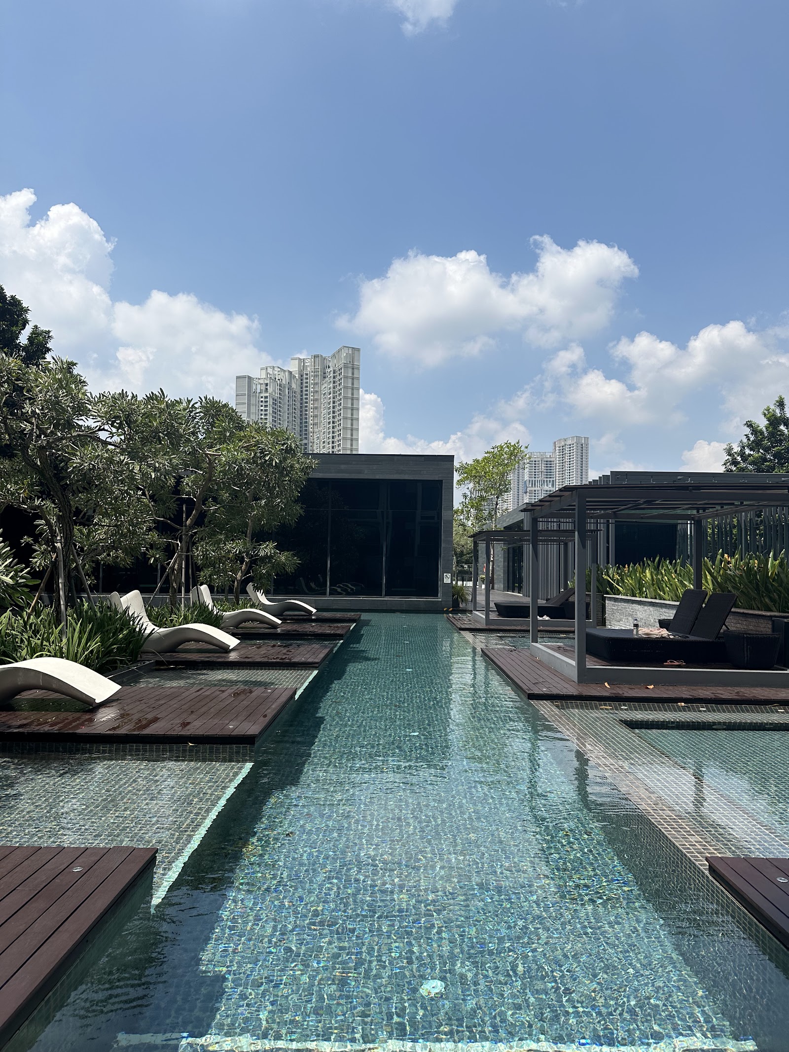 One Central Park @ Desa ParkCity: A rooftop swimming pool with lounge chairs and deck seating, surrounded by trees, with high-rise buildings visible in the background.