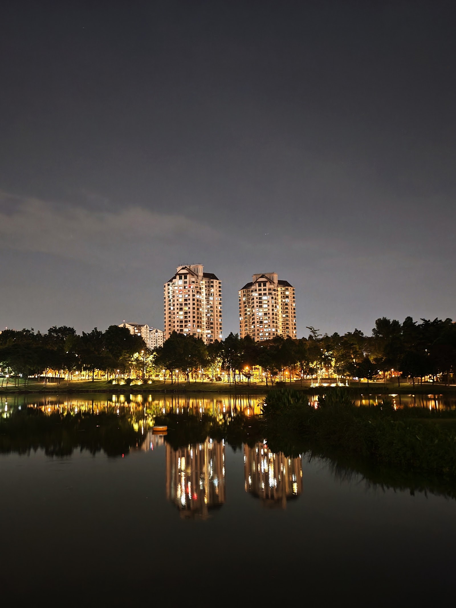 Nadia Parkfront: A night view of two high-rise residential towers reflected in a calm body of water in the foreground.