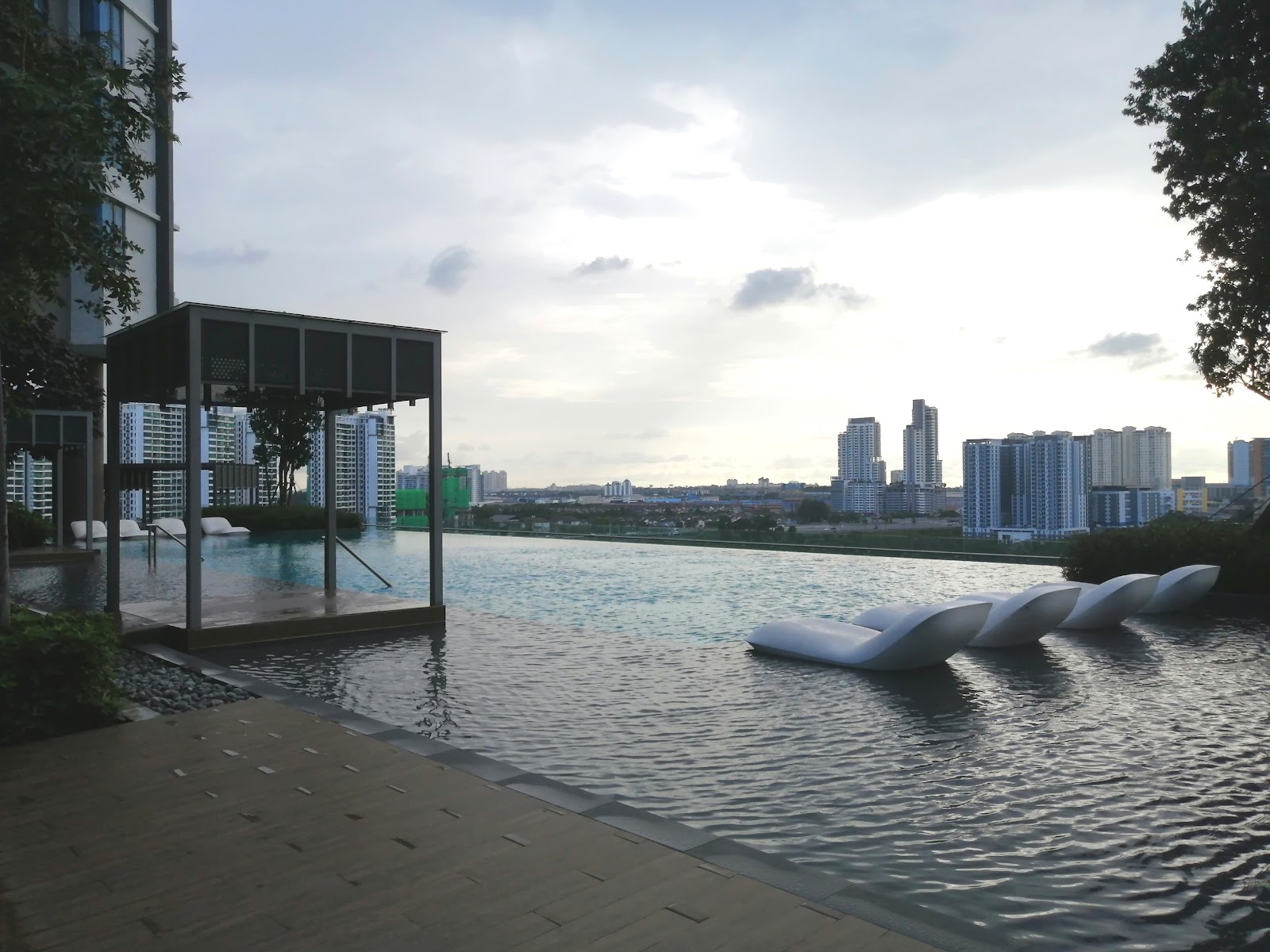 SUNWAY GEOSENSE: A rooftop infinity pool with white loungers and a pavilion, overlooking a city skyline at dusk.