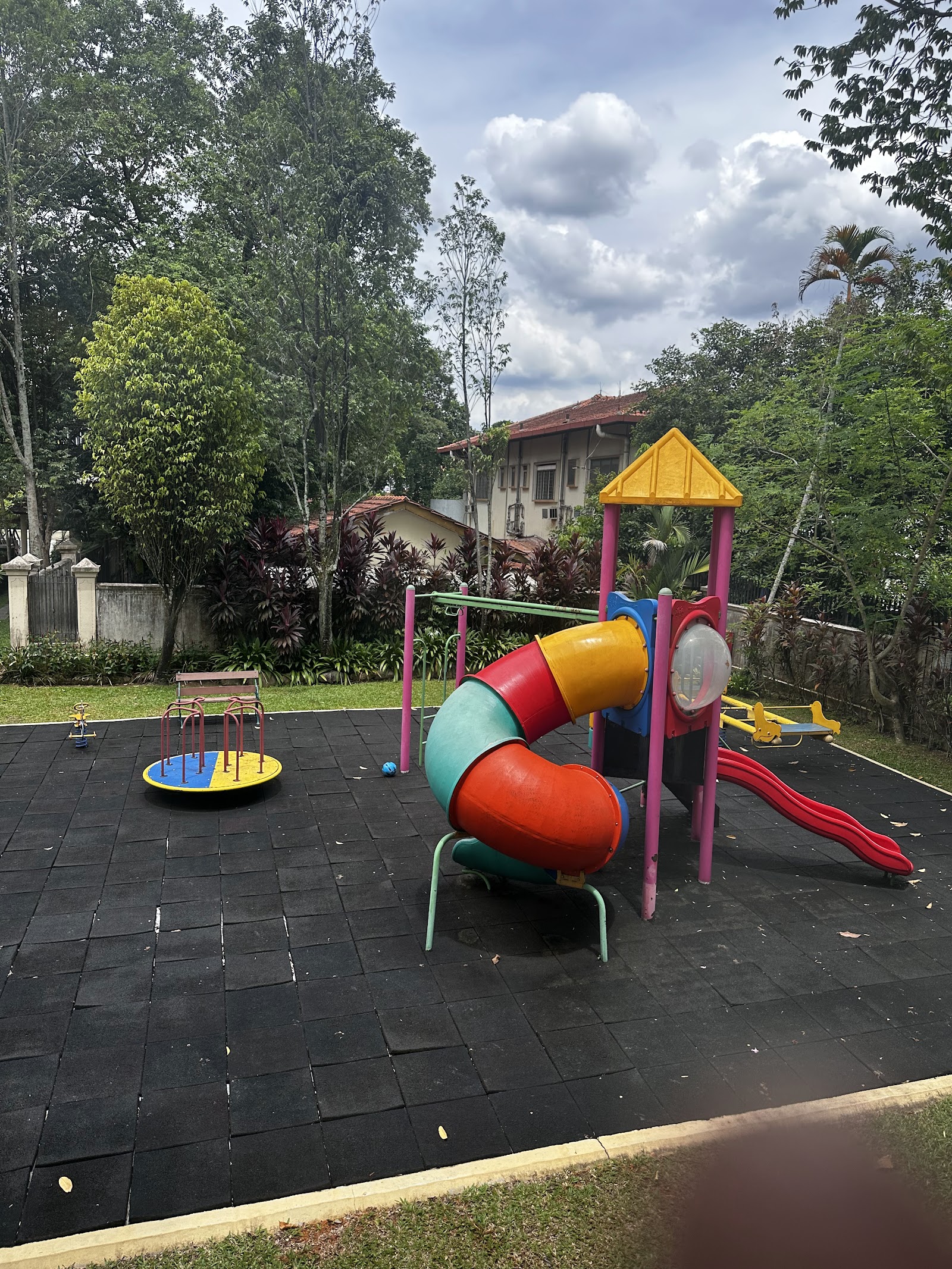 Regal Villa: A colorful children's playground featuring a slide, climbing structure, and spinner on a dark paved surface within a landscaped grounds area.
