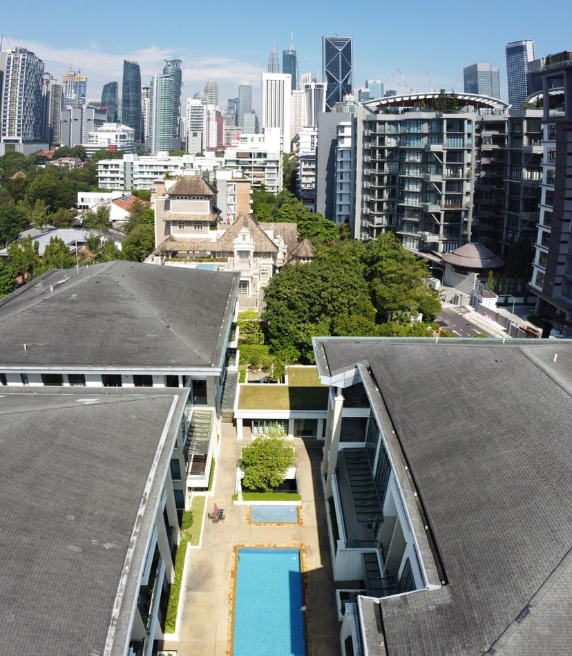 Madge Residences: An elevated view of a shared courtyard featuring a rectangular swimming pool and a central garden bed surrounded by the tiled roofs of the residence buildings.