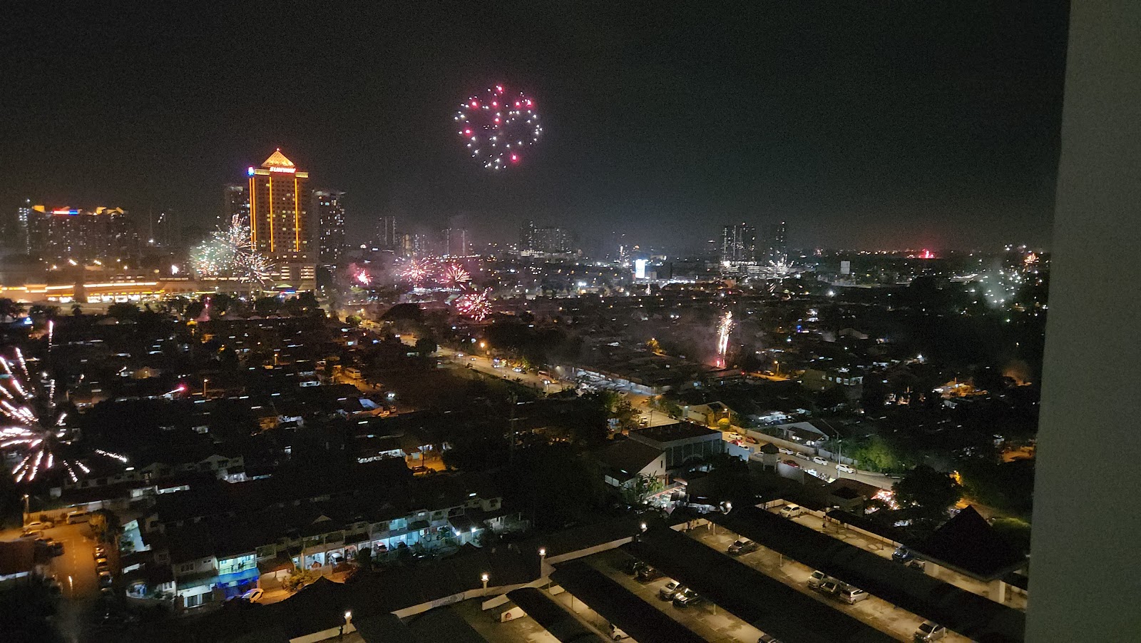 Ridzuan Condominium: A night view from a balcony overlooking a city skyline illuminated by lights and fireworks.
