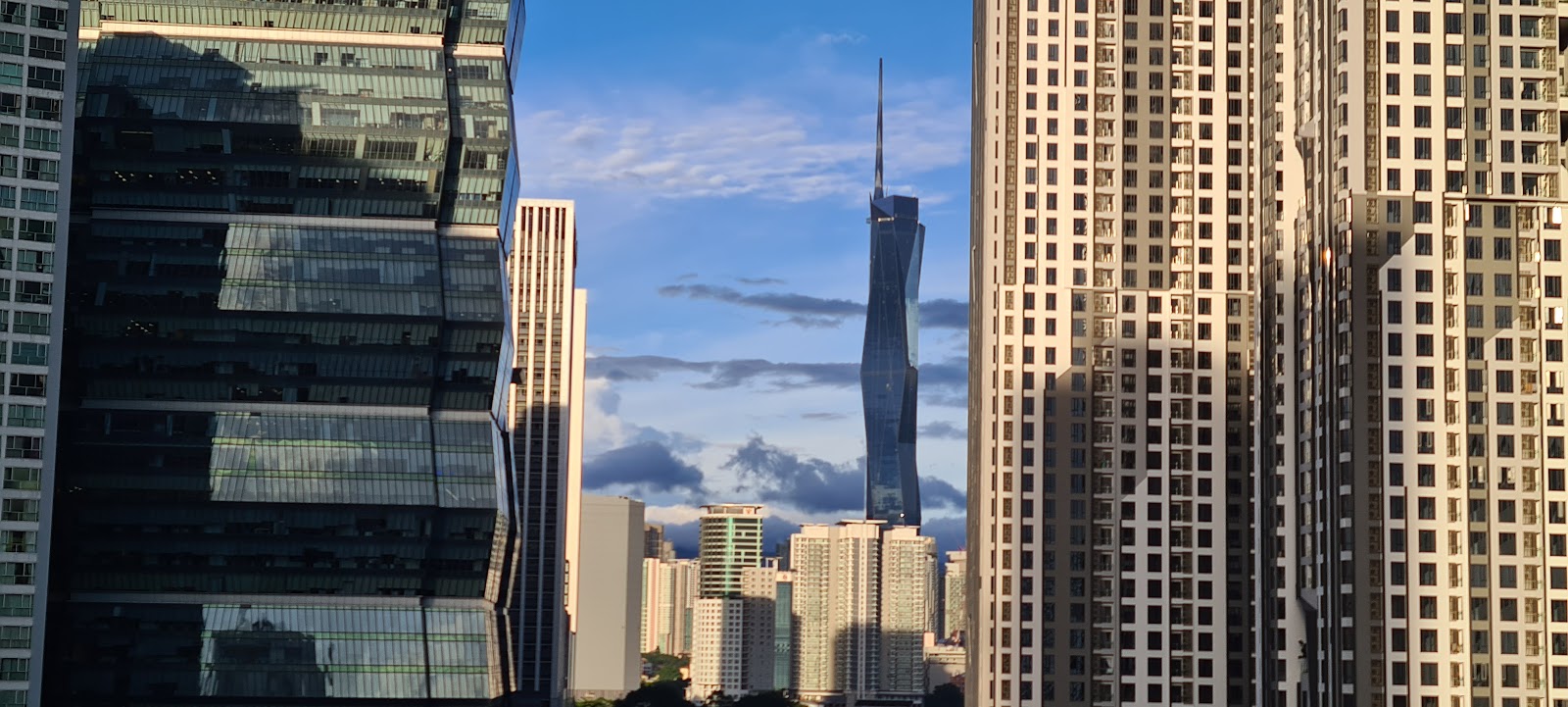 Crescent Court: A view from a high floor looking past neighboring skyscrapers towards a distinctive, twisted supertall building with a spire.